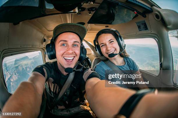 dos alegres amigos adultos jóvenes juntos en la cabina volando un pequeño avión de un solo motor - piloto fotografías e imágenes de stock