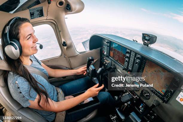 weitwinkelaufnahme einer fröhlichen jungen erwachsenen pilotin und fluglehrerin, die lächelt und ein kleines einmotoriges flugzeug fliegt - female pilot stock-fotos und bilder