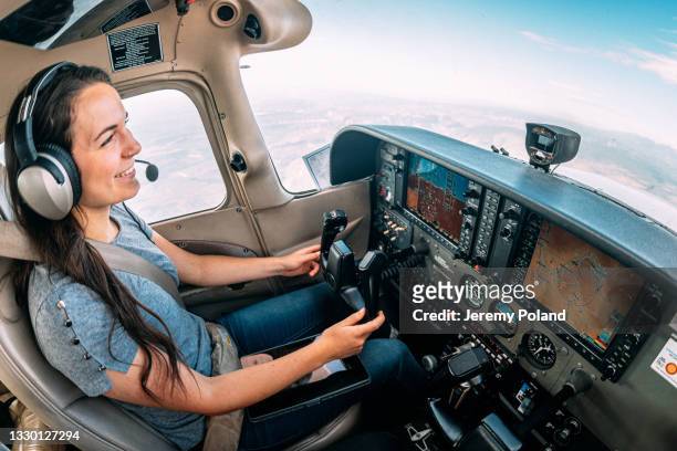toma gran angular de una joven piloto adulta alegre e instructora de vuelo sonriendo y volando un pequeño avión monomotor - piloto fotografías e imágenes de stock