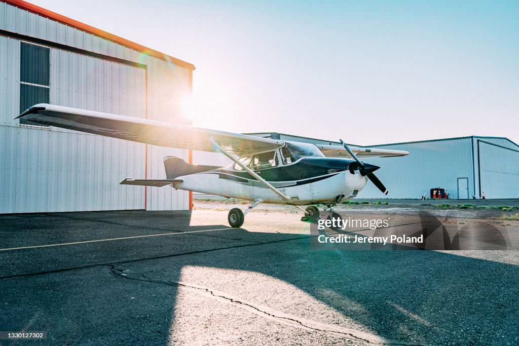 Sunrise Shot of a Small Single Engine Airplane Outdoors in Front of a Hangar