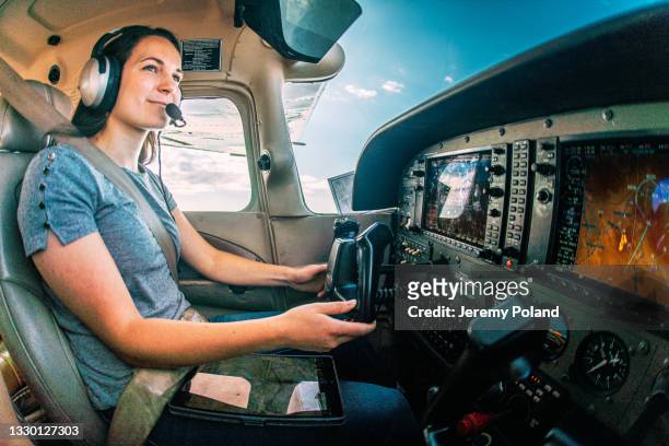 wide angle shot of a cheerful young adult female pilot flying a small single engine airplane - propellervliegtuig stockfoto's en -beelden