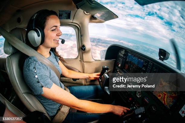 weitwinkelaufnahme einer fröhlichen jungen erwachsenen pilotin und fluglehrerin, die ein kleines einmotoriges flugzeug fliegt - privatflugzeug stock-fotos und bilder