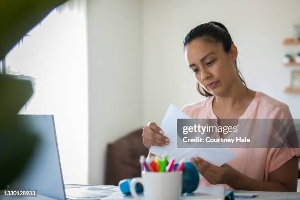 woman reads bills and letters while working from home - loan process stock pictures, royalty-free photos & images