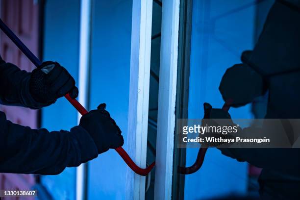 burglar with crowbar trying break the door to enter the house - thief stock pictures, royalty-free photos & images