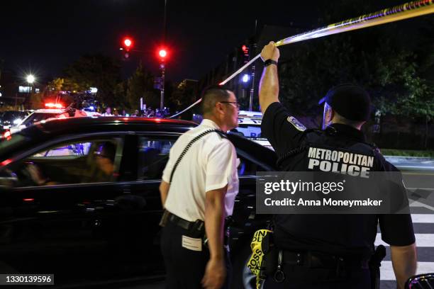 Police officer holds up caution tape near the site of a shooting on July 22, 2021 in Washington, DC. Gunfire erupted on a busy street, injuring two...