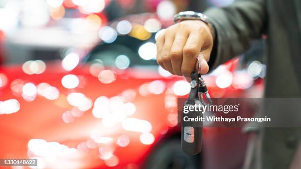 male holding car keys with car on background - car alarm stock-fotos und bilder