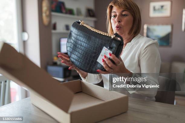 surprised woman holding new purse - handtas stockfoto's en -beelden