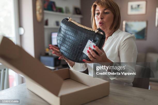 surprised woman holding new purse - luxury handbag stock pictures, royalty-free photos & images