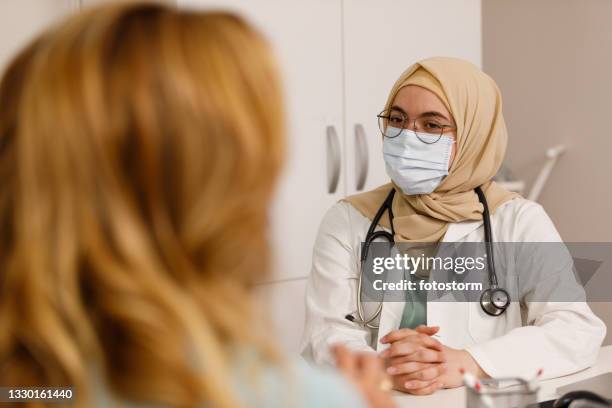 muslim female doctor having a conversation with a patient - primary care stock pictures, royalty-free photos & images