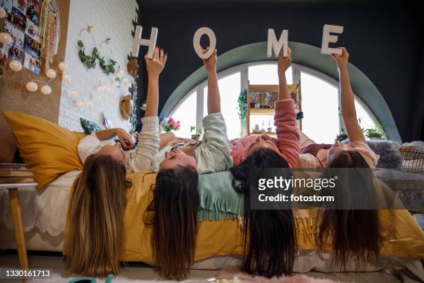 quatre copines tenant des lettres qui épellent « home » - vêtement de nuit photos et images de collection