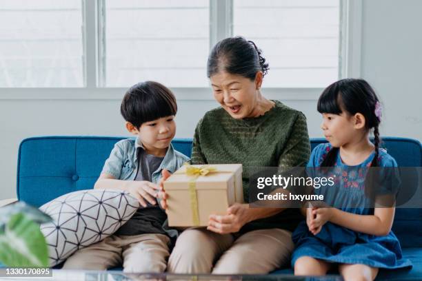 glückliche ältere asiatische frau erhält ein geschenk von ihren enkelkindern - chinese birthday stock-fotos und bilder