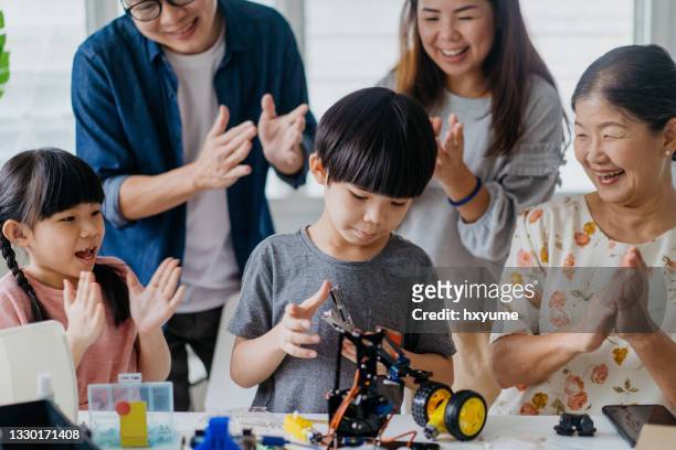 young boy building a robot toy together with his family members - school science project stock pictures, royalty-free photos & images