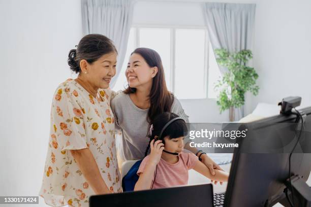 multi generation asian family video calling with computer at home - mother daughter webcam stockfoto's en -beelden