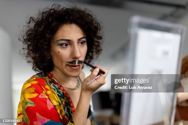 non binary person painting a mustache - körperbemalung stock-fotos und bilder
