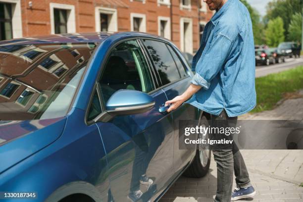 a man stands near his car and opens it - car front view stock pictures, royalty-free photos & images