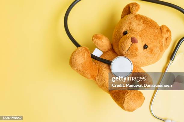 Stethoscope with Bear doll on yellow background for supporting kid living and illness. September Childhood Cancer Awareness month, healthcare and life insurance concept