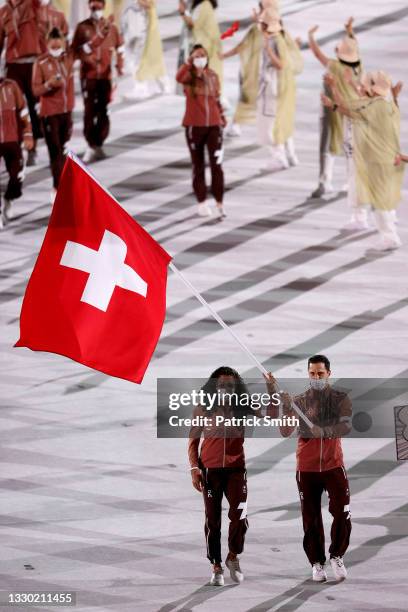 Flag bearers Mujinga Kambundji and Max Heinzer of Team Switzerland leads their team out during the Opening Ceremony of the Tokyo 2020 Olympic Games...