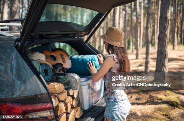 young woman unloading full truk with camping equipment - camping equipment stock pictures, royalty-free photos & images