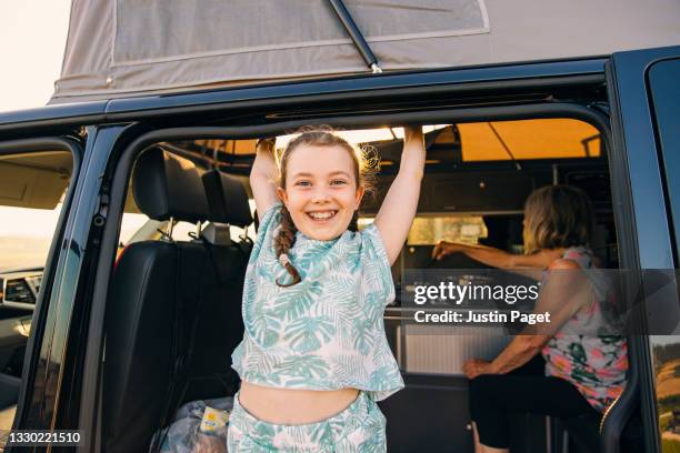 happy young girl smiling from her camper van - lieferwagen stock-fotos und bilder