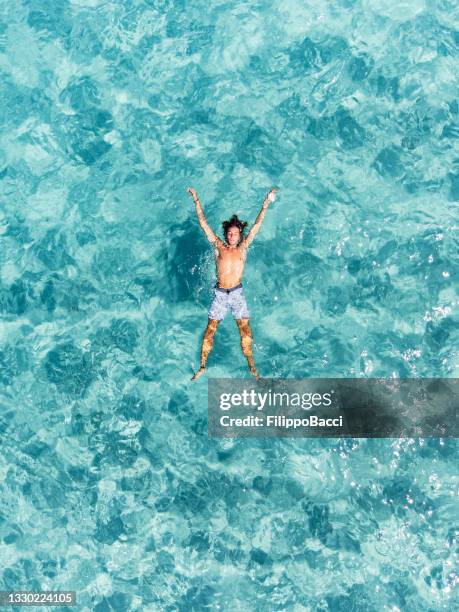 vista aérea de un hombre relajándose en un hermoso mar turquesa transparente - islas baleares fotografías e imágenes de stock