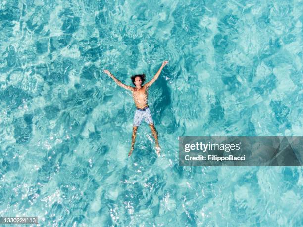 美しい透明なターコイズブルーの海でリラックスしている男の空中写真 - majorca ストックフォトと画像