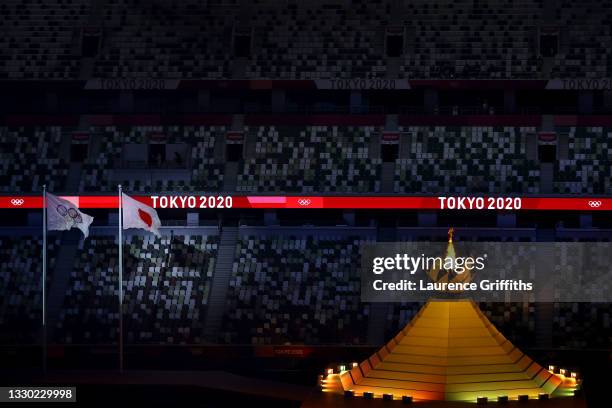 Detailed view of the Olympic cauldron lit next to the Japanese and Olympic flags during the Opening Ceremony of the Tokyo 2020 Olympic Games at...