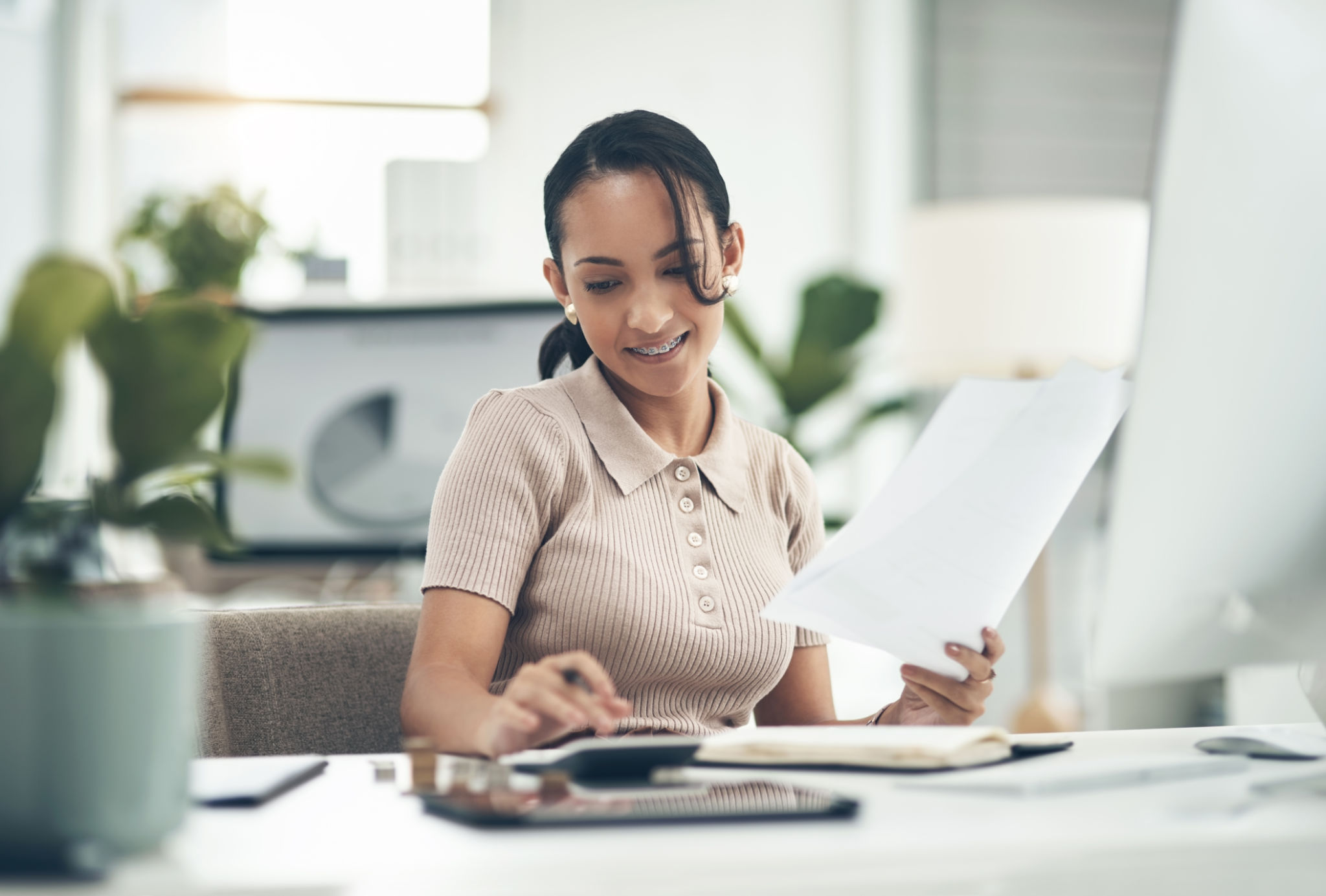 Shot of a young businesswoman calculating finances in an office Shot of a young businesswoman calculating finances in an office