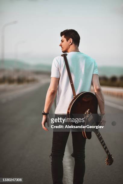modern guitarist walking with his instrument on highway - guitarist stock pictures, royalty-free photos & images