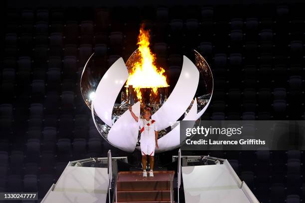 Naomi Osaka of Team Japan holds up the Olympic torch after lighting the Olympic cauldron during the Opening Ceremony of the Tokyo 2020 Olympic Games...