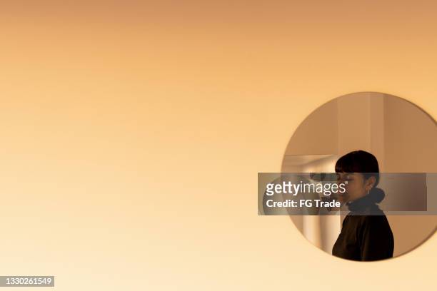 reflet d’une jeune femme sur un miroir rond près du mur - mur maison ombres photos et images de collection