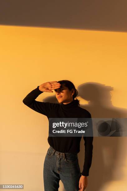 woman indoors covering eyes because of bright light - guess who stock pictures, royalty-free photos & images