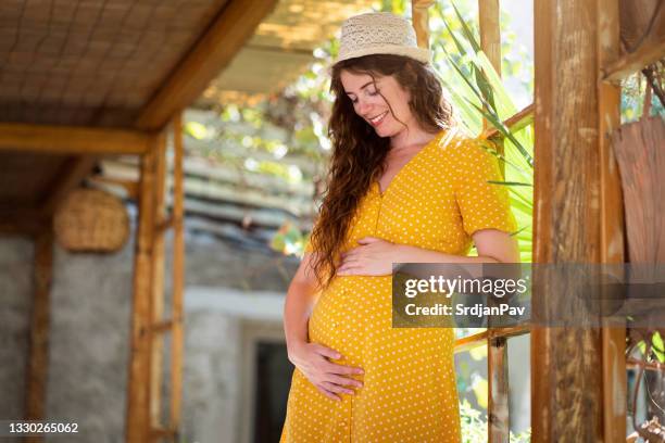 portrait of one pregnant caucasian woman standing in her yard - girly pregnant stock pictures, royalty-free photos & images