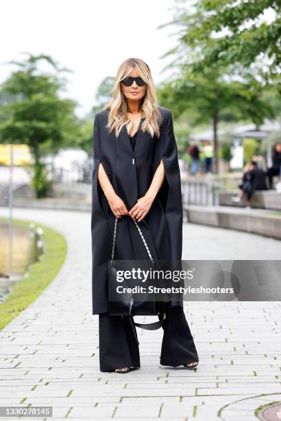 Influencer Gitta Banko wearing a black cape by Givenchy, a black silk top by Givenchy, black wide leg pants by Gucci, a black bag with silver chain...