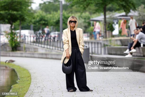 Influencer Gitta Banko wearing a beige oversized blazer by Petar Petrov, a black tank top by Petar Petrov, black wide leg pants by Petar Petrov,...