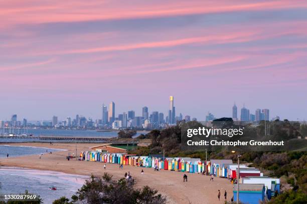 brighton beach bathing boxes with the skyline of melbourne at dusk - groenhout melbourne stock pictures, royalty-free photos & images