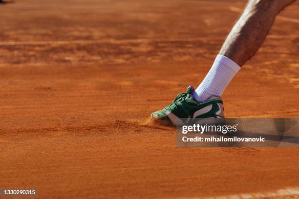 un tenista deslizándose sobre tierra batida - running shoe fotografías e imágenes de stock