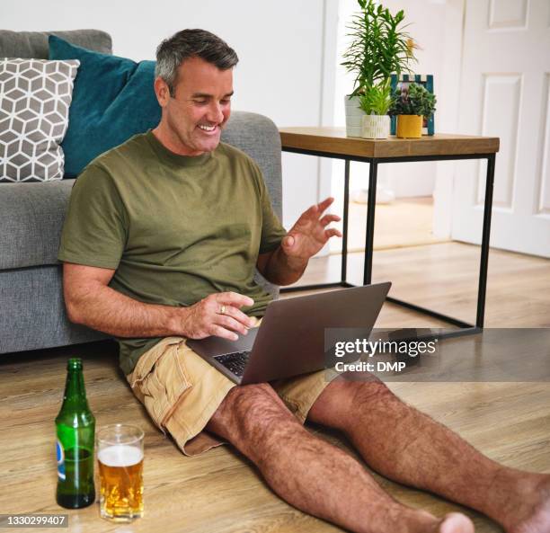 shot of a mature man using a laptop to make a video call while relaxing in the living room at home - 2020 glasses stock pictures, royalty-free photos & images