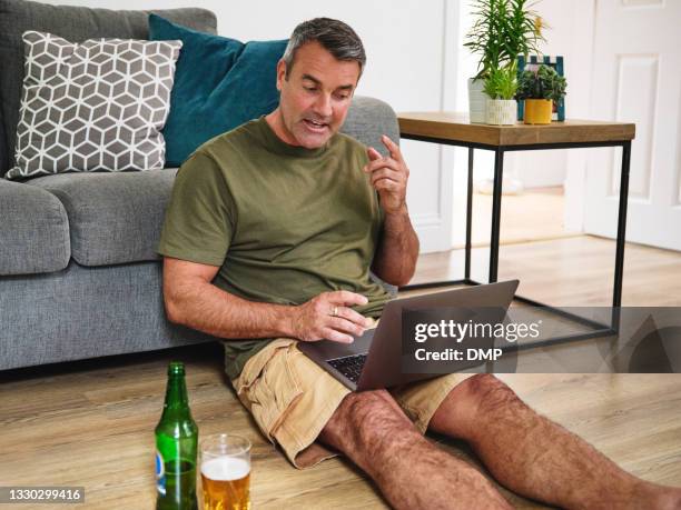 shot of a mature man using a laptop to make a video call while relaxing in the living room at home - 2020 glasses stock pictures, royalty-free photos & images