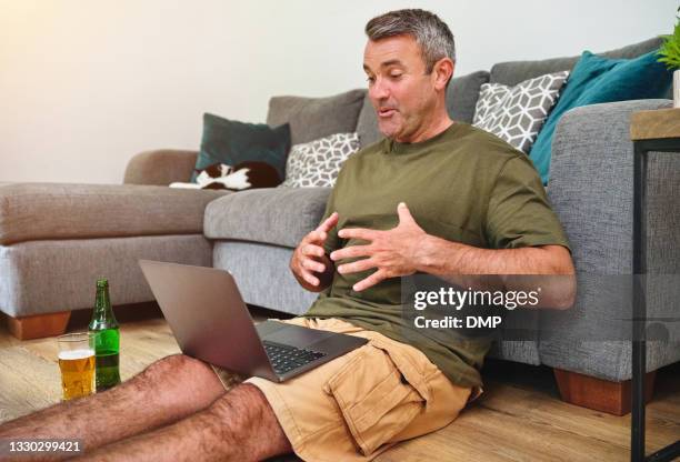 shot of a mature man using a laptop to make a video call while relaxing in the living room at home - 2020 glasses stock pictures, royalty-free photos & images