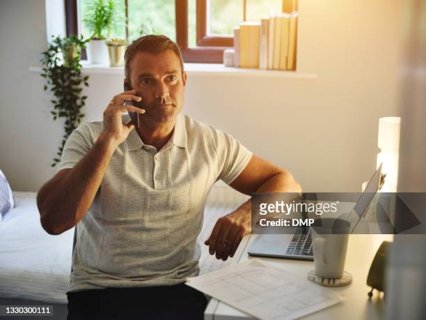 shot of a mature man using a smartphone and laptop while working at home - 2020 vision stock pictures, royalty-free photos & images