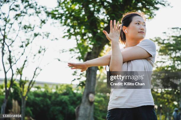 asian woman stretching after/before jogging in a park - precalentamiento fotografías e imágenes de stock