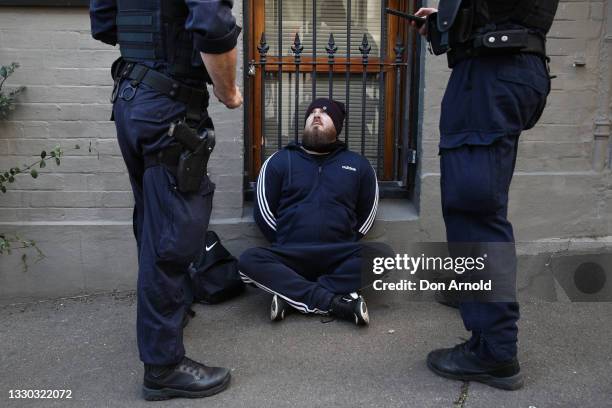 Man is questioned by police in a Camperdown back street on July 24, 2021 in Sydney, Australia.Anti-lockdown and anti-vaccination activists gathered...