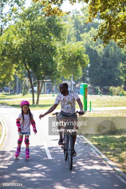 father and daughter enjoy sunny day together - adult riding bike through park stock pictures, royalty-free photos & images