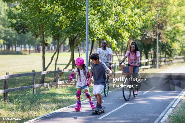 weekend with family - mother and daughter riding on skateboard in park stock pictures, royalty-free photos & images