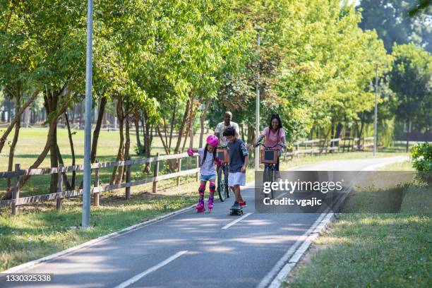 family sports day - mother and daughter riding on skateboard in park stock pictures, royalty-free photos & images