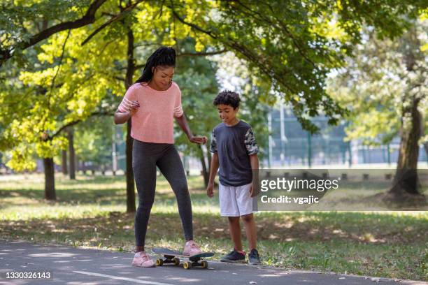 süßer 10-jähriger junge lernt seine mutter skateboarding - 10 11 years boy stock-fotos und bilder