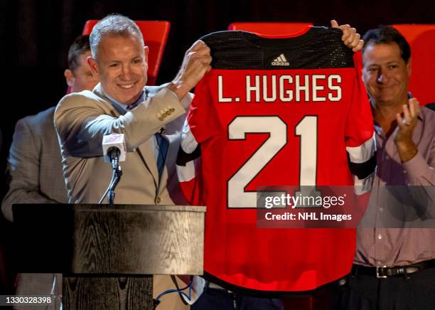 General manager Tom Fitzgerald holds up the jersey of Luke Hughes, chosen fourth overall by the New Jersey Devils during the first round of the 2021...