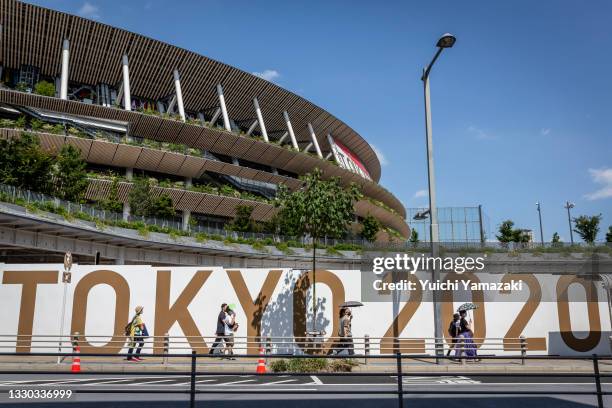 People walk past an Olympics branded wall outside of Olympics Stadium on July 24, 2021 in Tokyo, Japan. As the postponed Tokyo Olympics get underway...