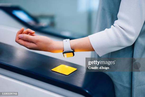 close up of young asian woman checking in at subway station, making a quick and easy contactless payment for subway ticket via smartwatch. nfc technology, tap and go concept - plataforma de estação de metro imagens e fotografias de stock