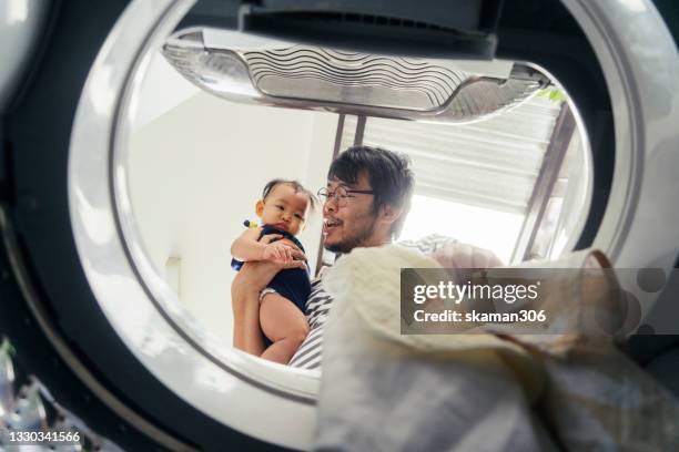 low angle view from inside washing machine asian single father embracing daughter feeling concern and boring about baby apron dirty and often to cleaning - leanincollection father photos et images de collection